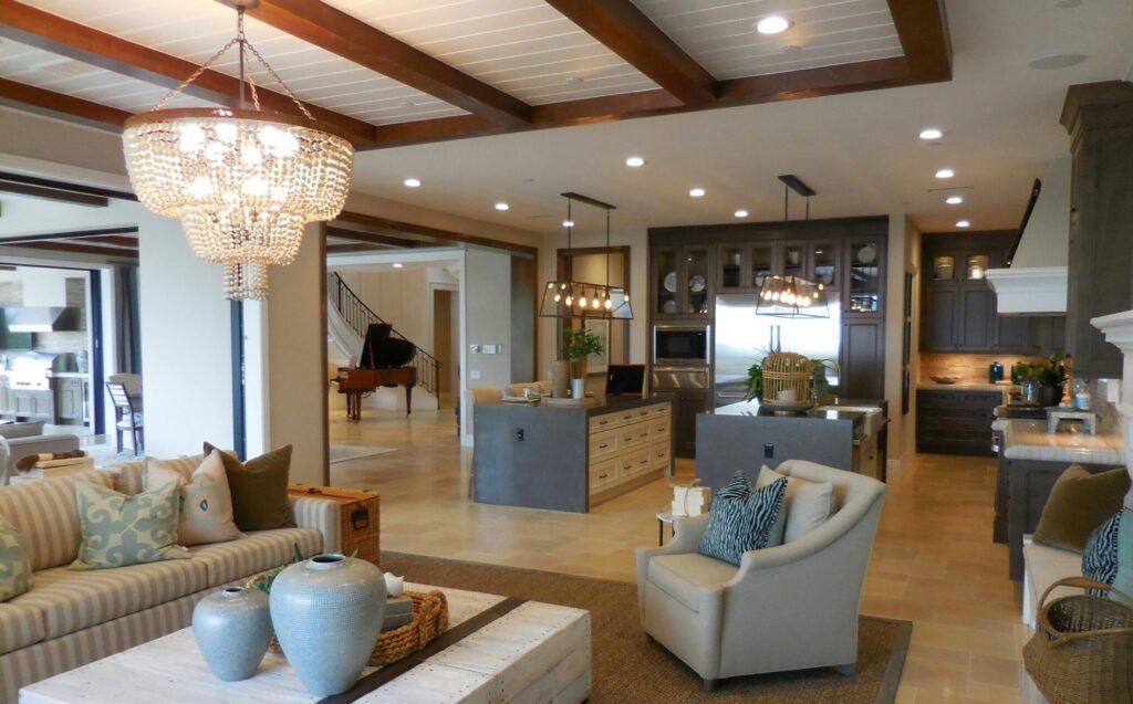 Spacious living room with elegant decor and an open kitchen area, featuring a chandelier and comfortable furnishings.